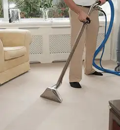 Professional carpet cleaner using a hot-water extraction wand and hose machine in a living room in Bellevue, WA.