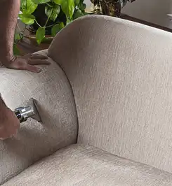 Professional upholstery cleaner deep-cleaning a fabric sofa with a handheld extraction tool and hose Bellevue, WA.
